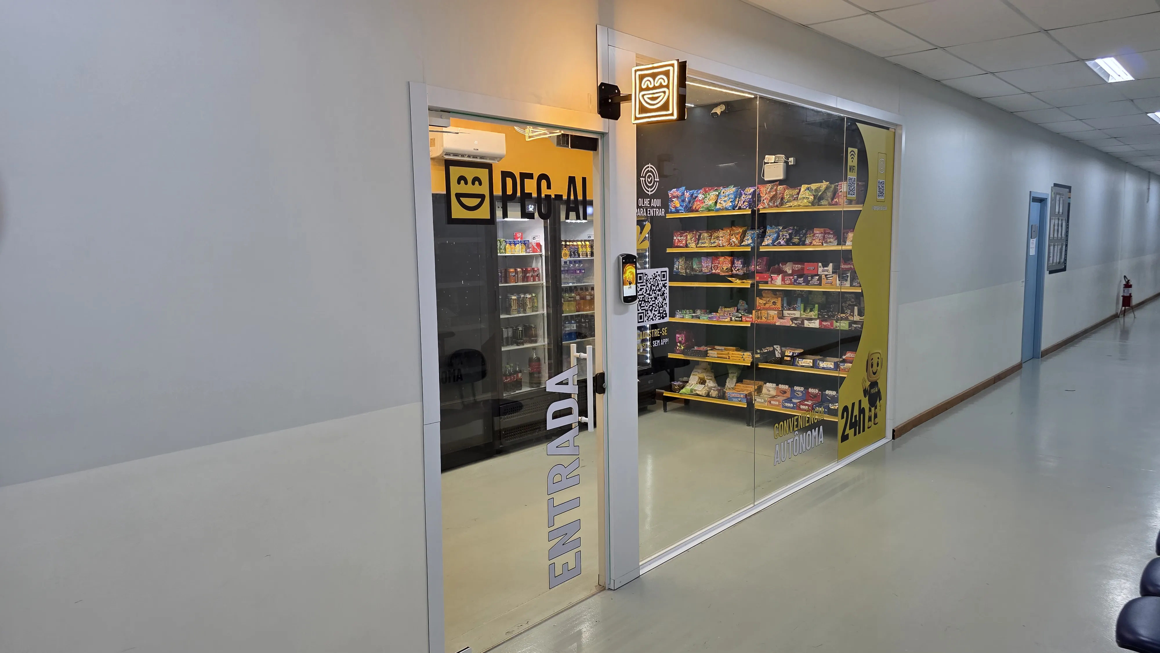 Loja PEG-AI em corredor de empresa, com porta de vidro, letreiro neon e prateleiras de produtos visíveis